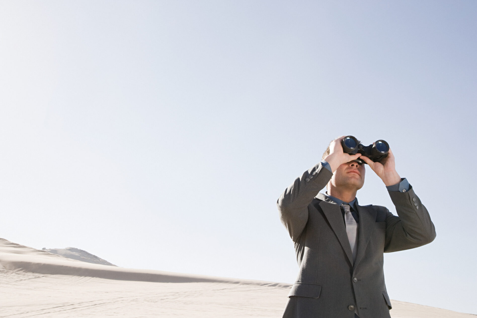 Businessman in desert with binoculars